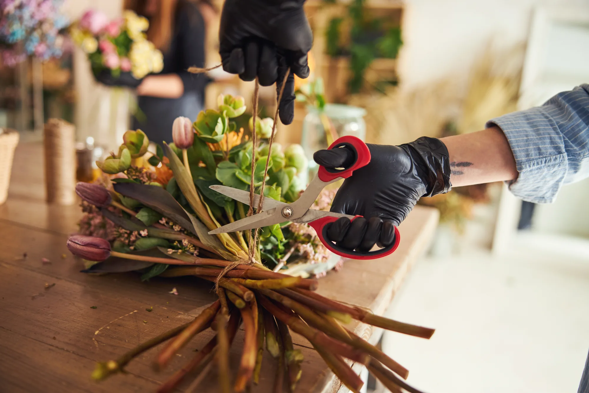 Fleuriste attachant un bouquet coloré sur sa table de travail.