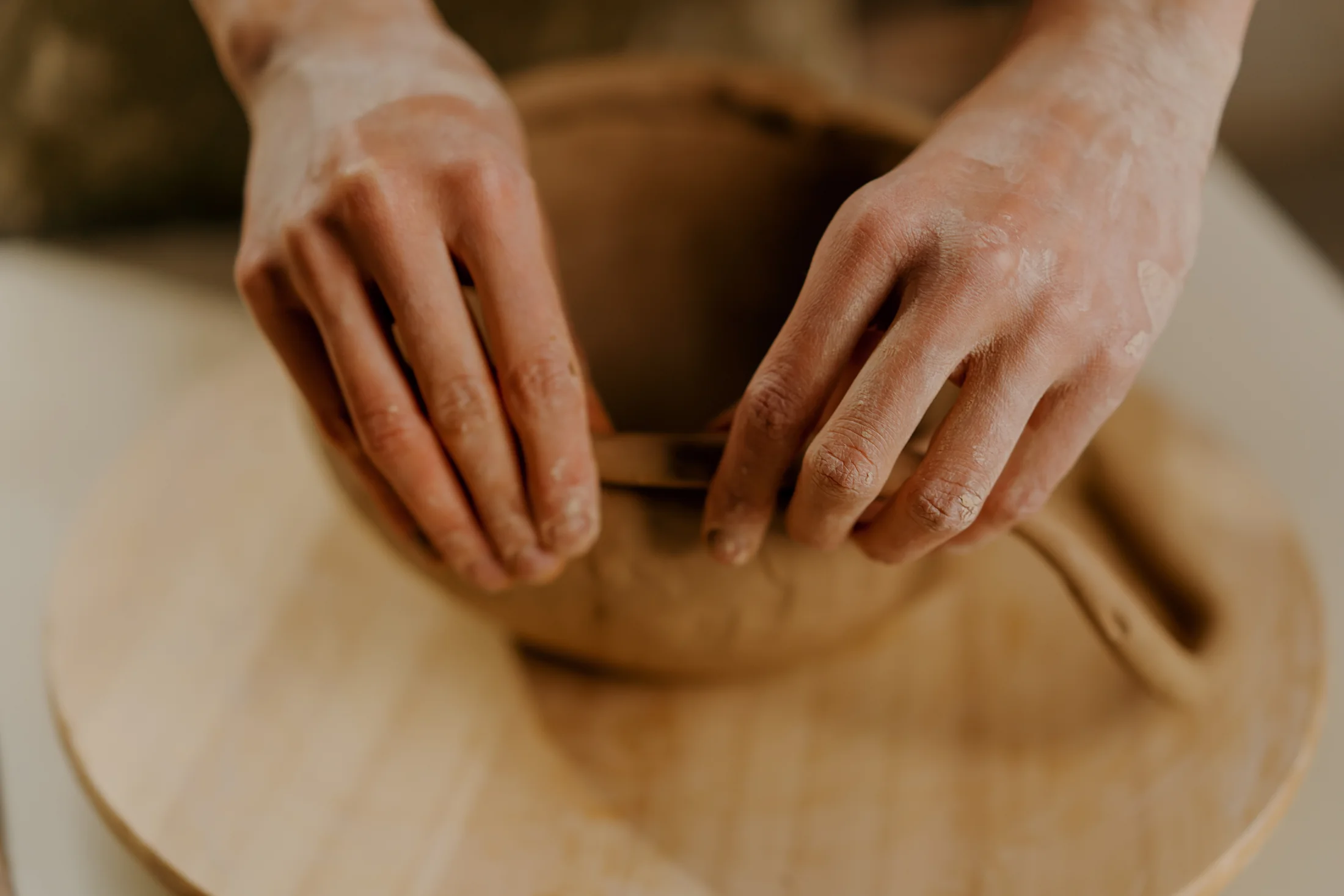 Mains d’une céramiste façonnant une pièce en argile.